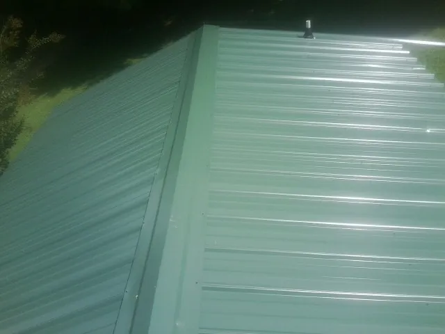 New green metal panels meeting at the ridge of a roof — Flat Roof Repair work by our crew in Paoli