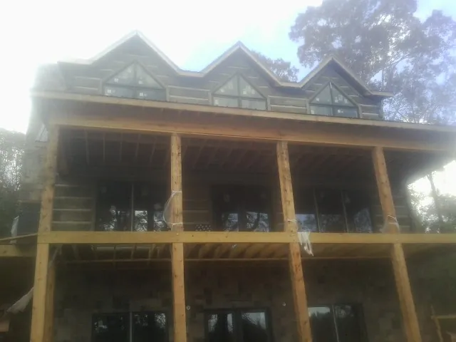 Dormers and porch framing on a large log home under construction — Roof Coating work by our crew in Paoli