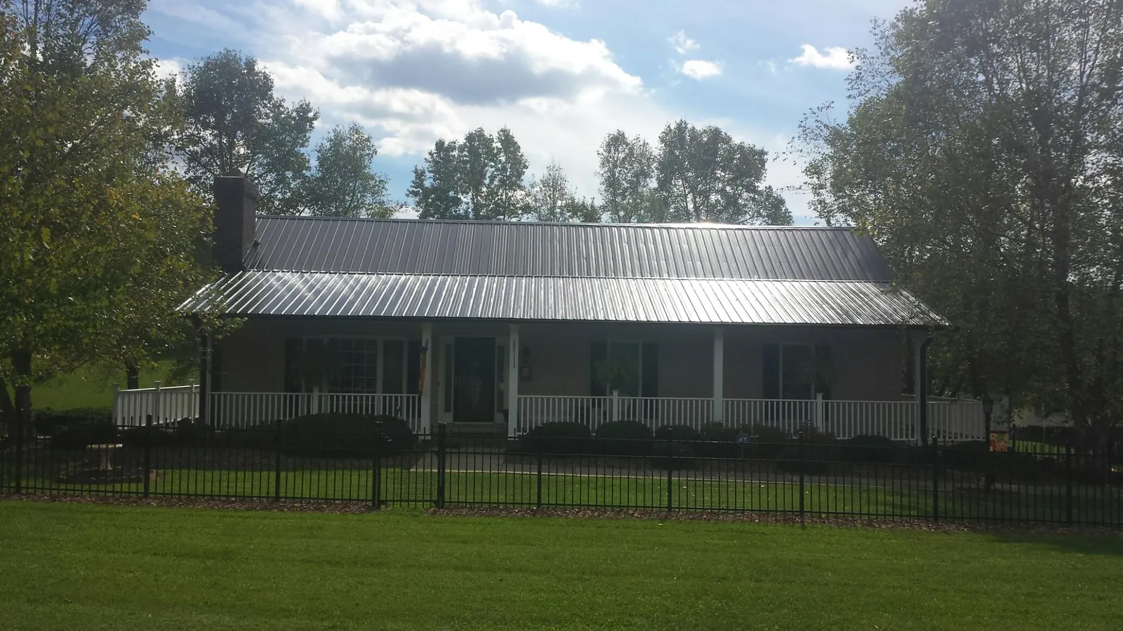 Gray metal roof on a brick ranch with a full width front porch — Gutter Guard Installation work by our crew in Paoli