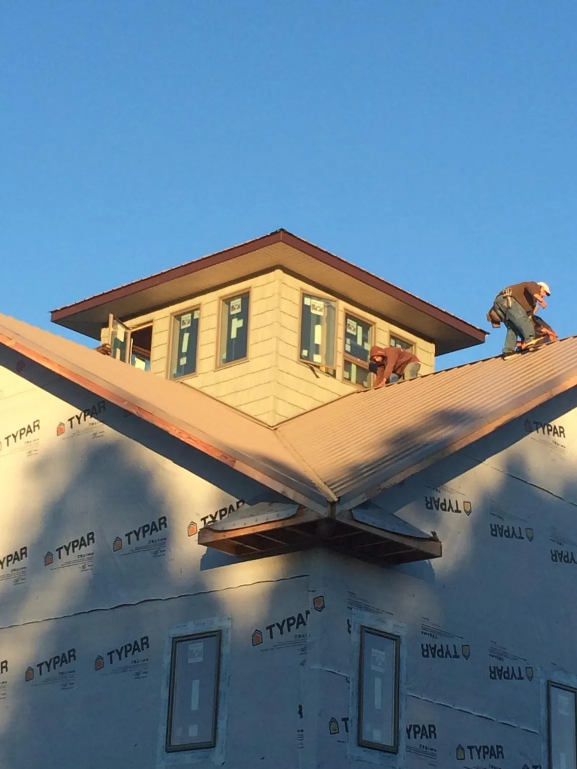 Roofers working around a rooftop cupola on a new metal roof at sunset — Roof Waterproofing in Paoli by Roofing Brothers